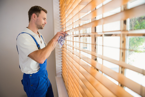Image of a man cleaning blinds